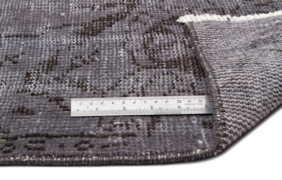 Charcoal and grey distressed rug with a traditional medallion pattern, shown with a metal ruler for scale.