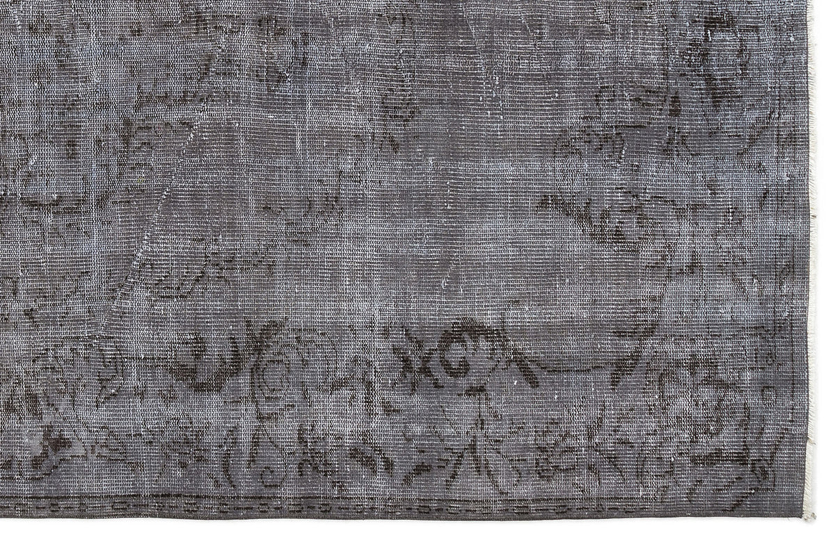 Charcoal grey rug with a faded, distressed traditional medallion pattern and a visible fringe edge.