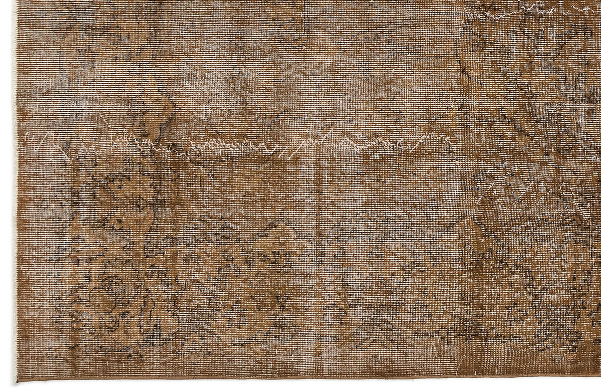 Brown and white distressed rug with a faded traditional medallion pattern.
