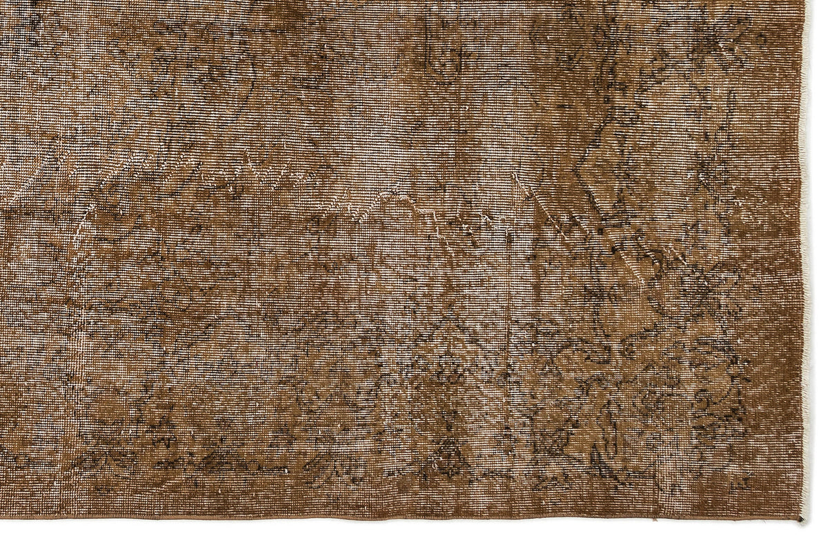 Brown distressed rug with a faded traditional medallion pattern and white fringe edge.
