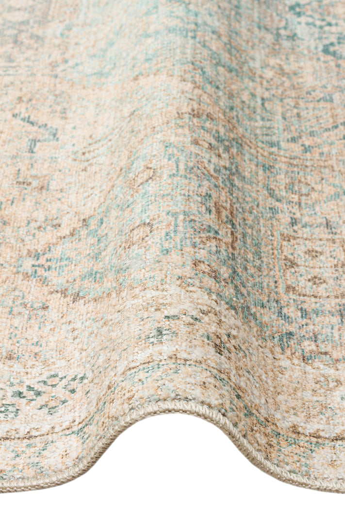 Beige and teal distressed traditional medallion rug with a folded edge on a white background.