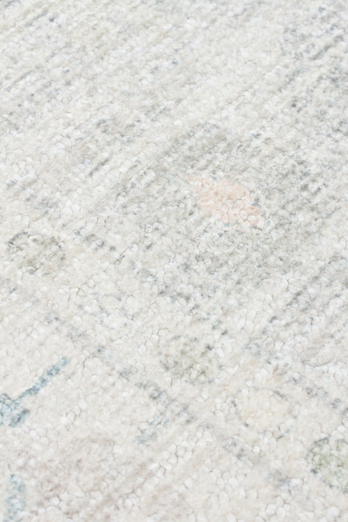 Bild 1 in Galerieansicht laden. Close-up of a high-pile cream rug with a distressed, faded pattern in soft grey, blue, and pale pink accents.