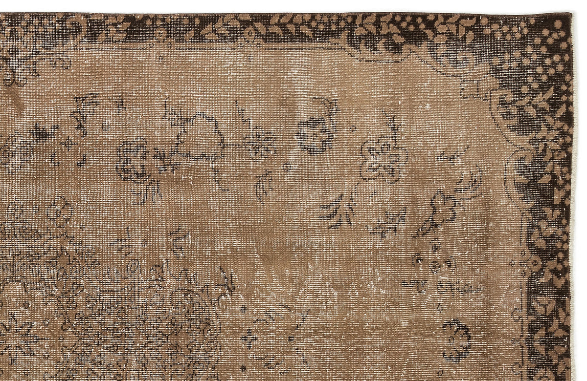 Distressed brown and dark brown rug with a faded floral border and scattered botanical motifs.