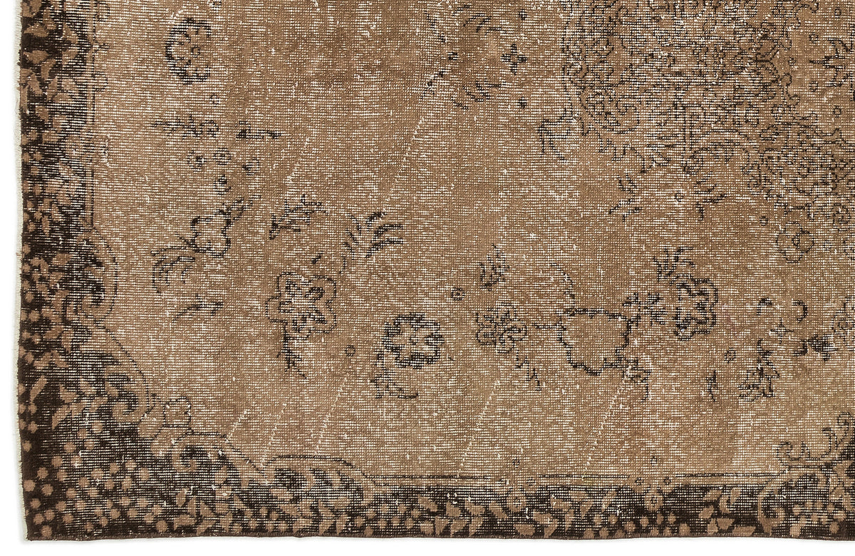 Distressed brown and dark espresso rug with a faded floral medallion pattern and a decorative border.
