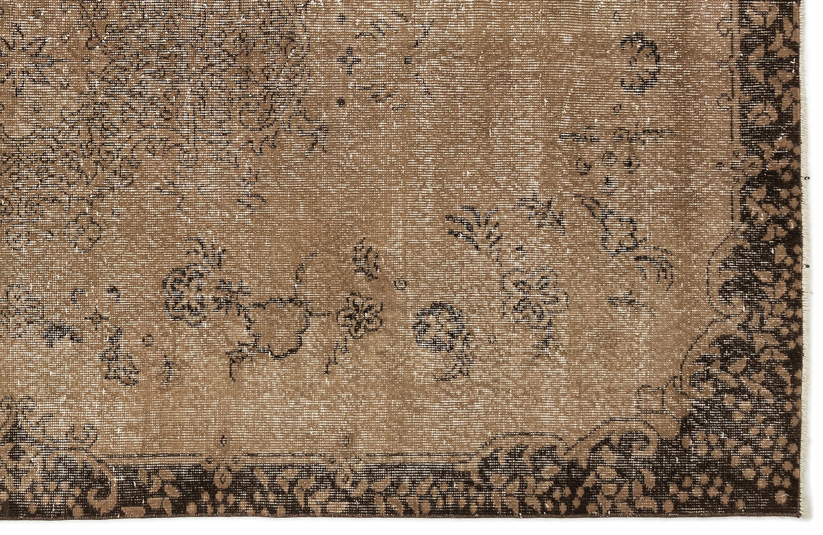 Distressed brown and dark chocolate rug with a faded floral medallion pattern and a wide decorative border.
