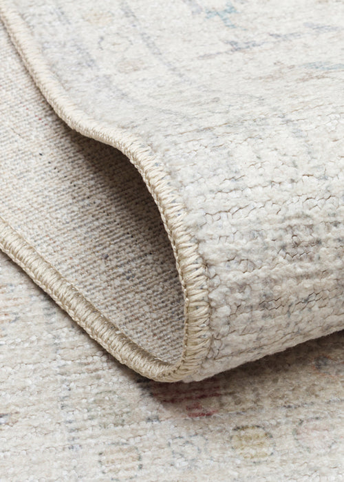 Bild 1 in Galerieansicht laden. Close-up of a cream and beige rug with a textured pile, showing a folded corner with a finished stitched edge.