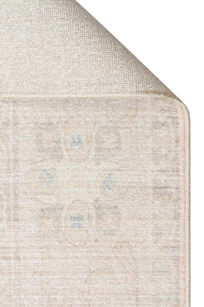 Beige and cream area rug with a faded traditional medallion pattern and a visible woven backing, isolated on white.