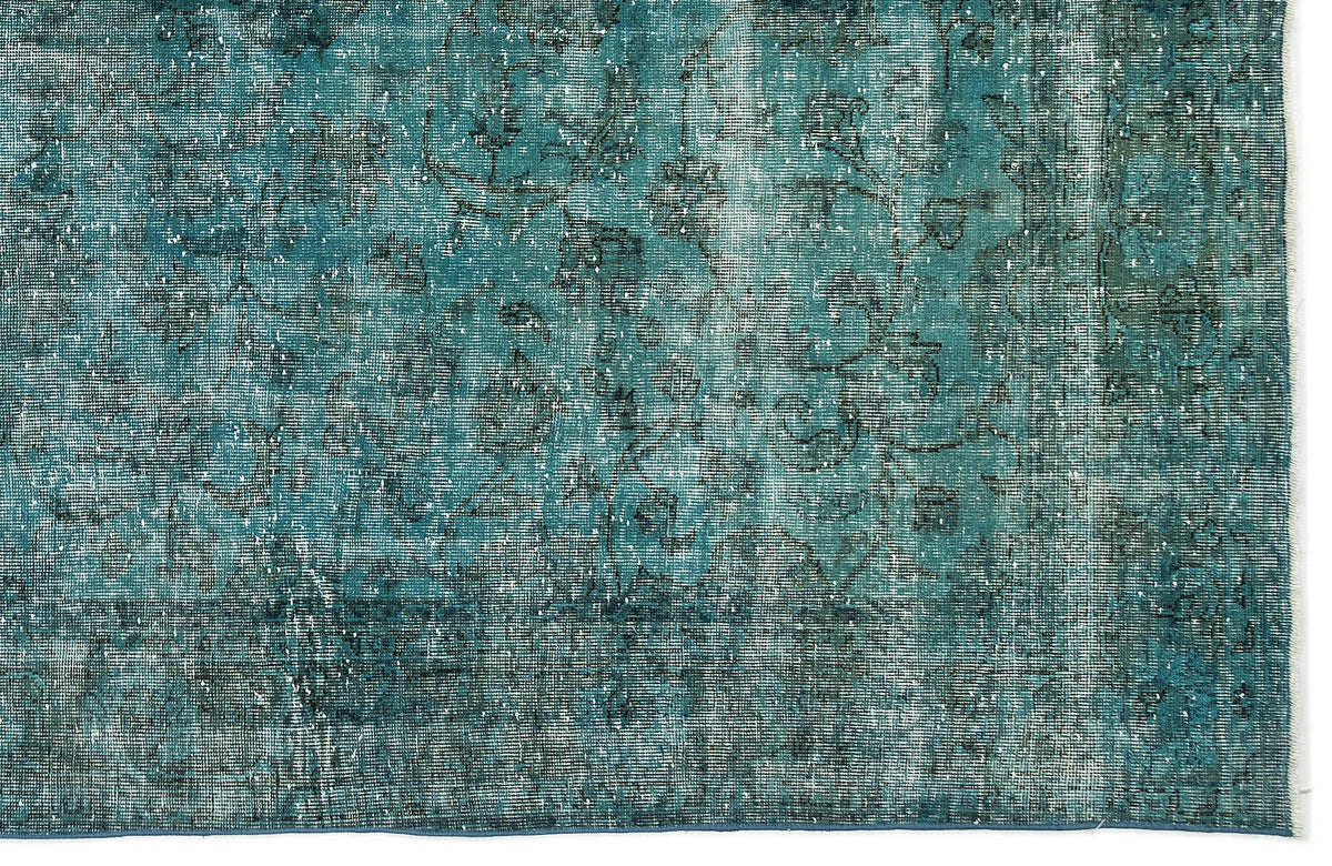 Teal and black distressed rug with a faded traditional floral pattern.