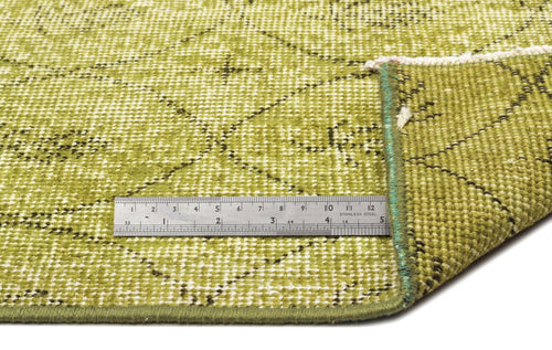 Load image 1 in gallery view. Olive green rug with a distressed diamond pattern and a metal ruler for scale, showing the texture and edge finish.