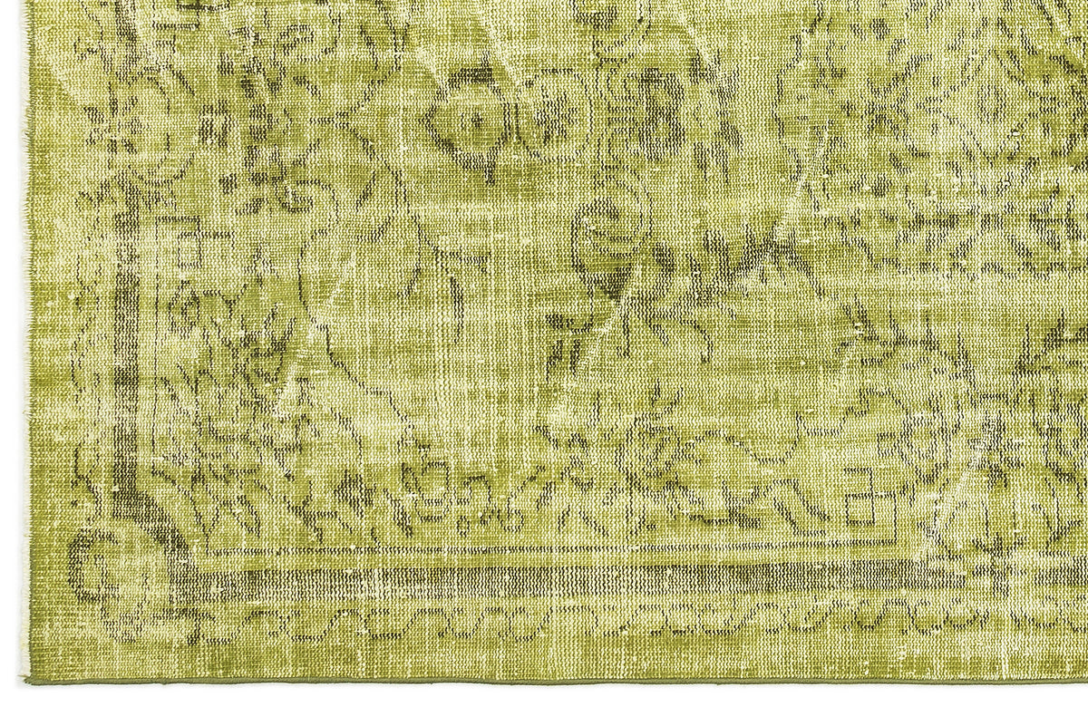 Chartreuse and olive green distressed rug with a faded traditional floral medallion pattern.