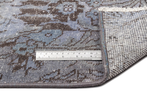 Load image 1 in gallery view. Blue and charcoal distressed floral rug with a folded corner showing the backing and a metal ruler for scale.