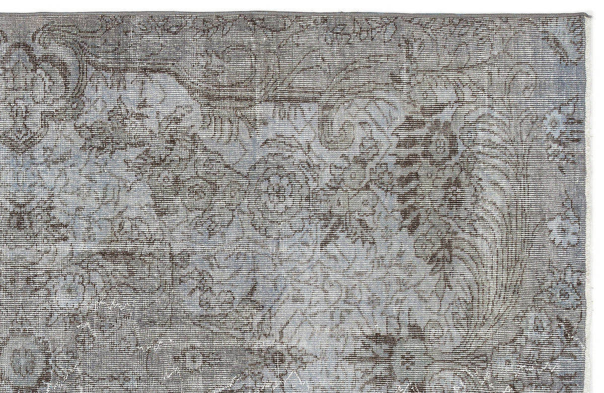 Grey and charcoal distressed rug with a faded traditional floral medallion pattern on a white background.