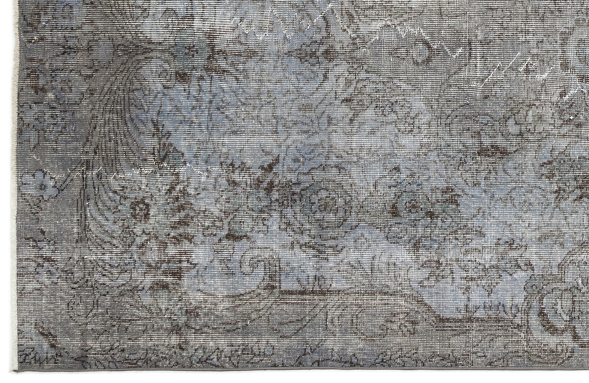 Blue and charcoal grey rug with a distressed, faded floral medallion pattern and a fringed edge.