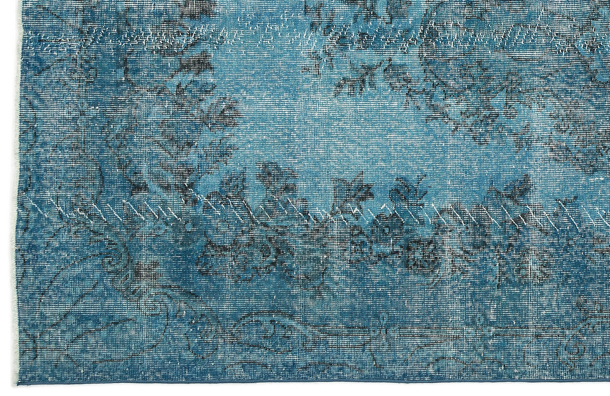 Teal and blue distressed rug with a faded floral pattern and visible white stitched repair lines.