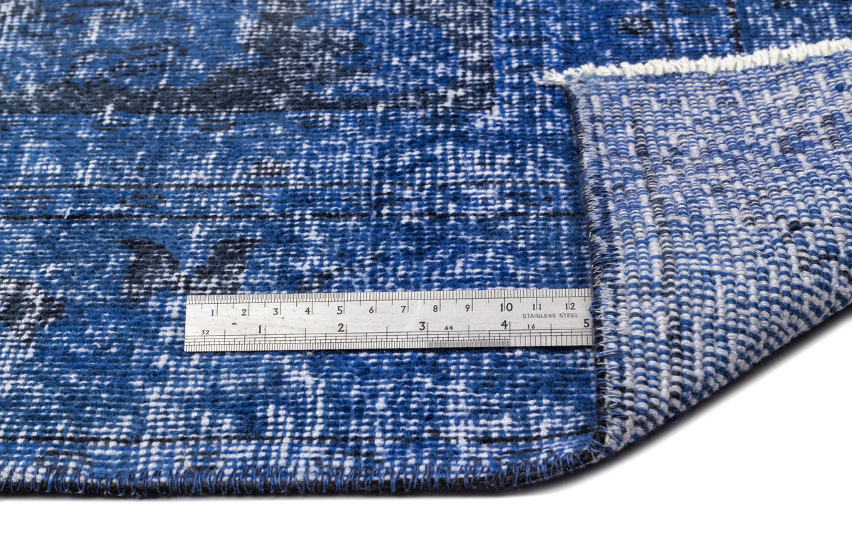 Distressed blue and black rug with a white woven backing, shown with a metal ruler for scale.
