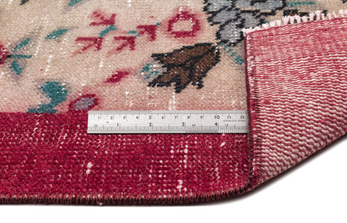 Load image 1 in gallery view. Beige and deep red floral rug with a distressed finish, showing the underside and a metal ruler for scale.