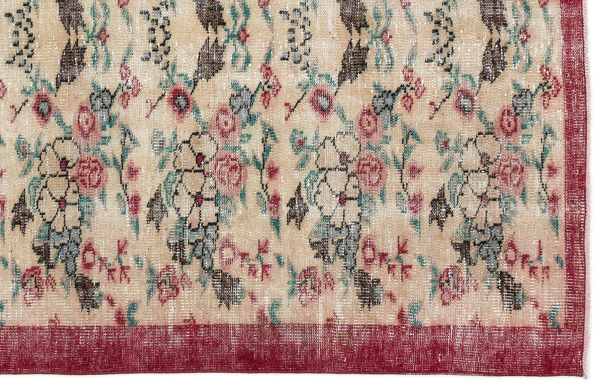 Beige rug with a distressed floral pattern in red, teal, and charcoal, featuring a solid red border.