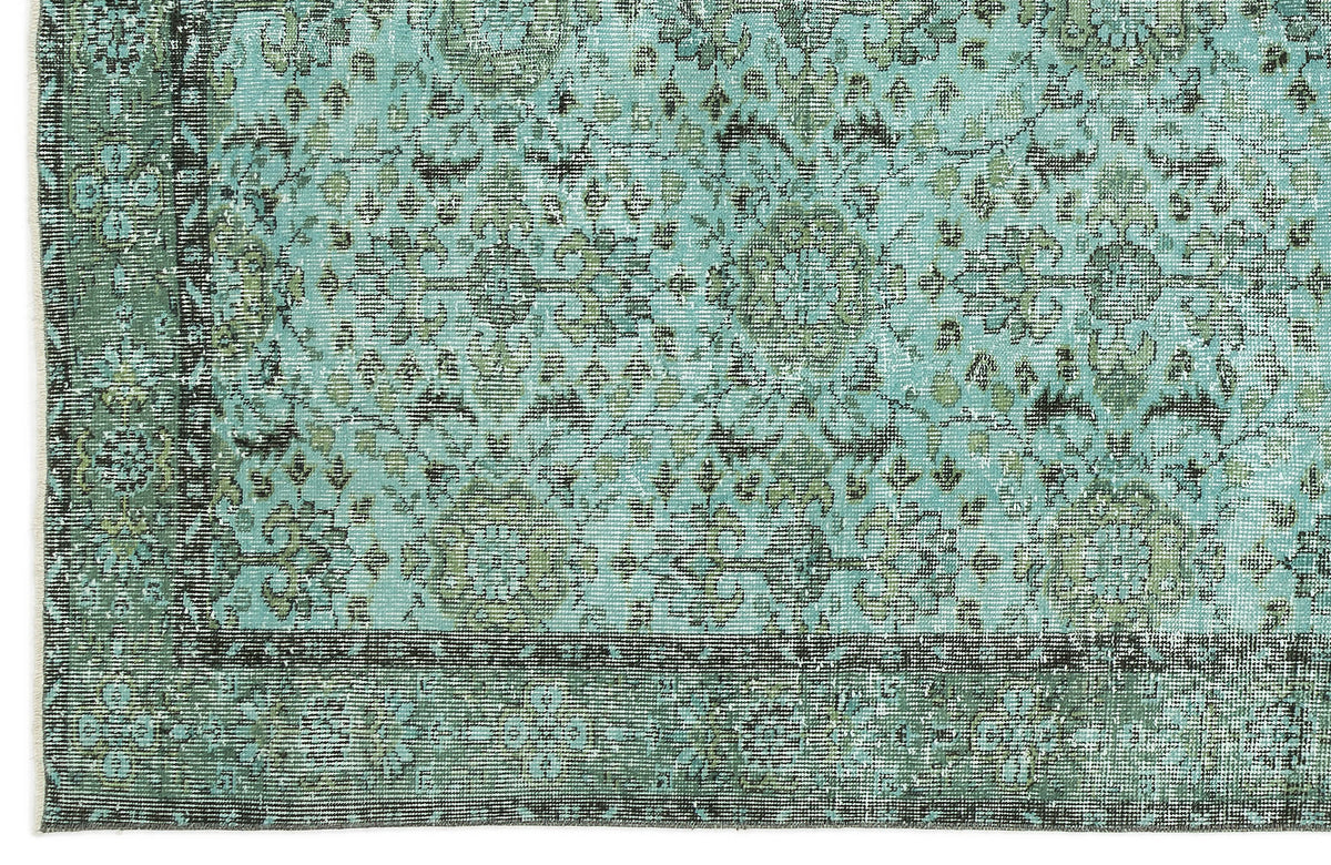 Distressed turquoise and olive green rug with a traditional floral medallion pattern and a dark border.