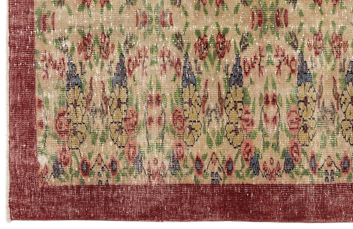 Distressed beige rug with a floral pattern in red, green, and blue, featuring a solid dark red border.