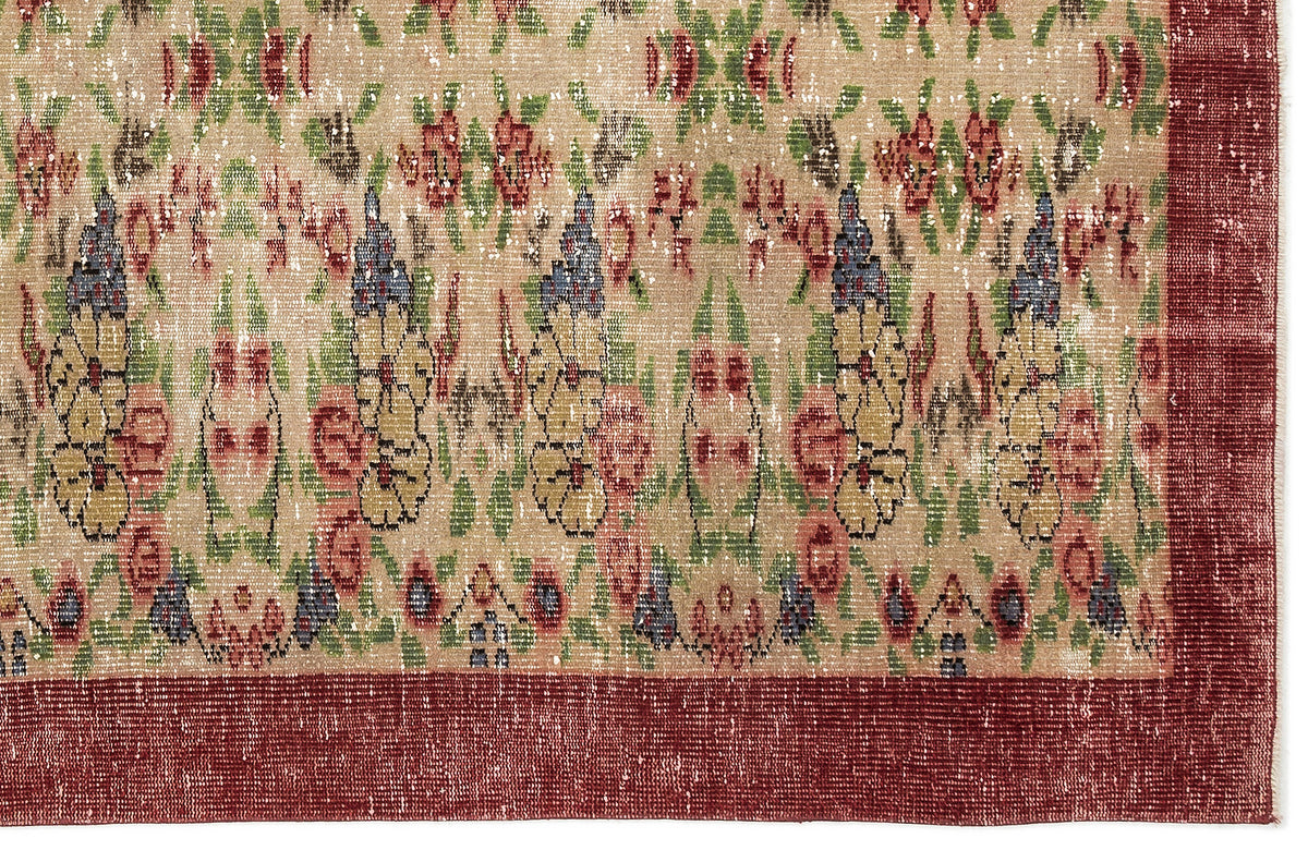 Distressed beige rug with a multi-colored floral pattern in red, green, and blue, featuring a solid dark red border.