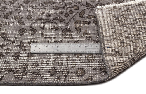Load image 1 in gallery view. Grey and charcoal distressed floral pattern rug with a metal ruler showing pile height and backing detail.