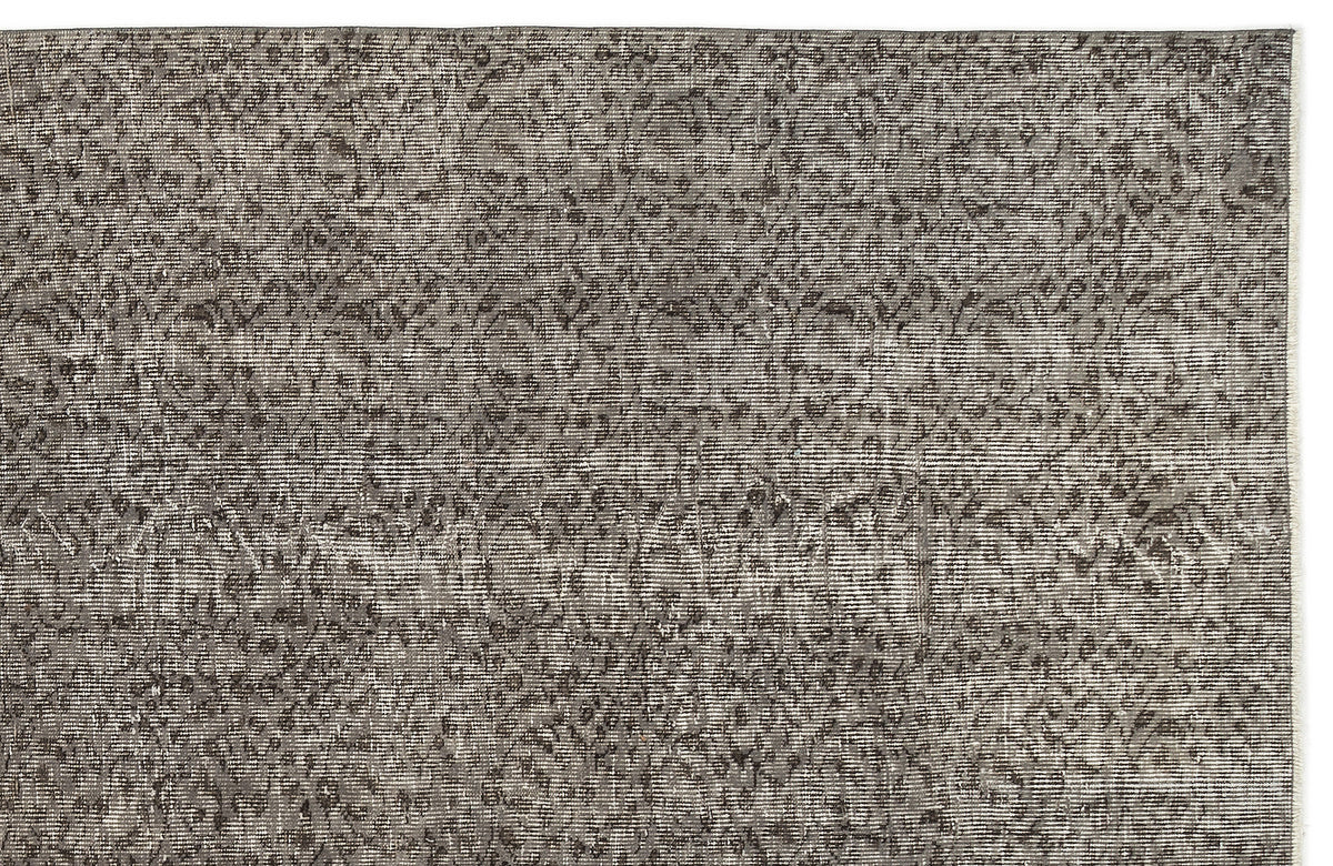 Charcoal and grey distressed rug with a faded, intricate traditional floral pattern.