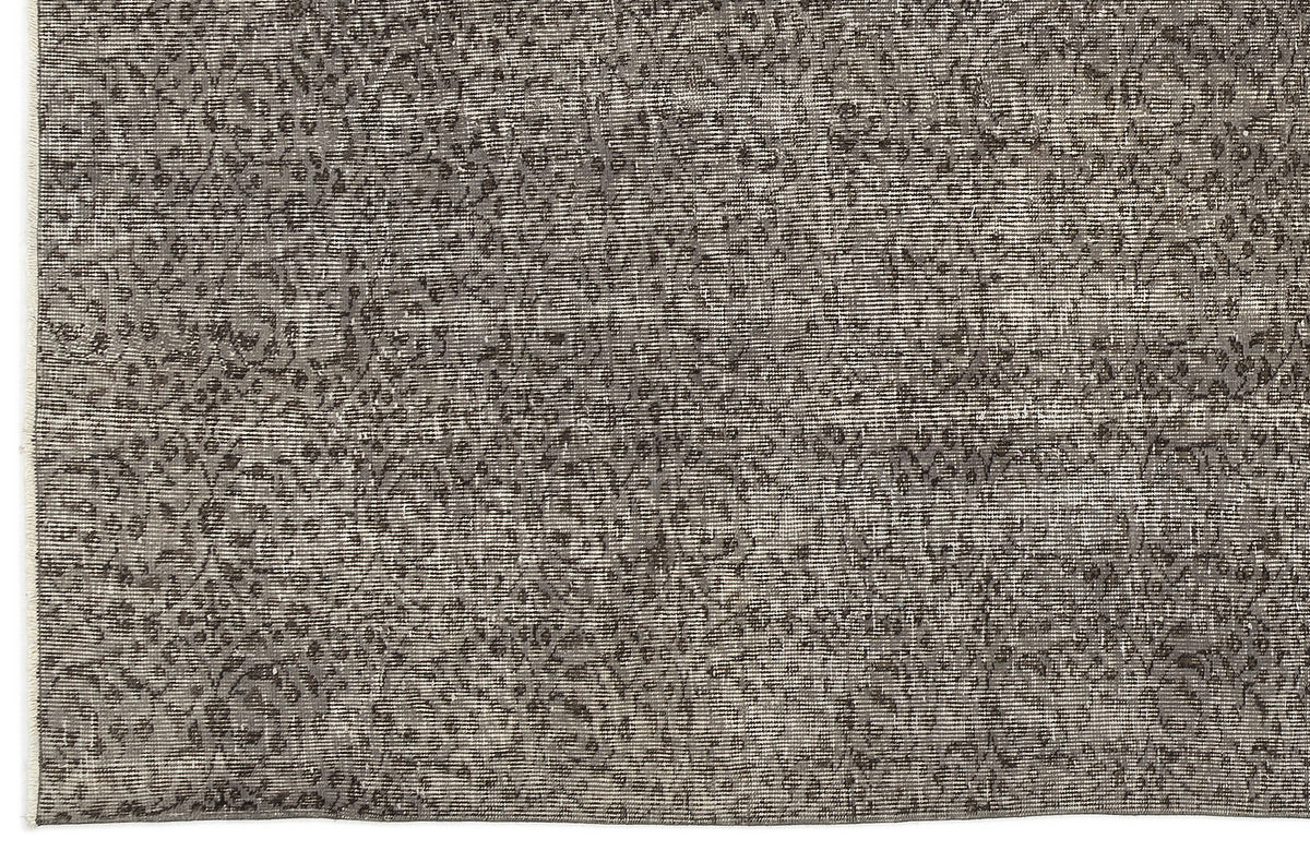 Charcoal and grey distressed rug with a faded, traditional floral medallion pattern.