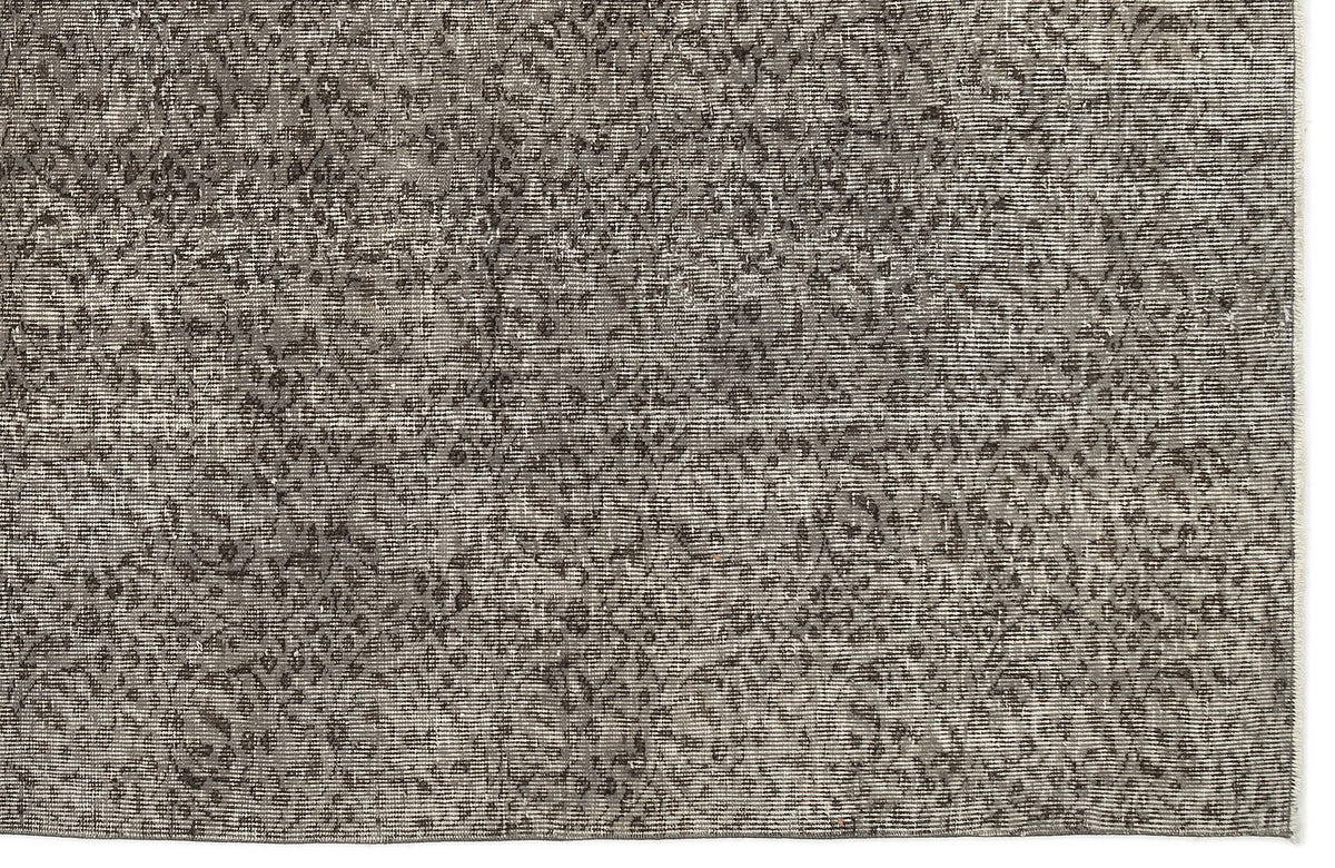 Charcoal and grey distressed rug with a faded, intricate traditional medallion pattern.