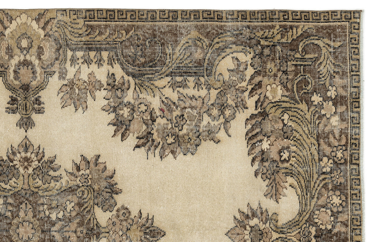 Beige and brown traditional rug with a floral medallion pattern and a geometric Greek key border.