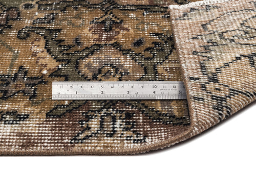 Load image 1 in gallery view. Brown and olive green traditional rug with a distressed floral pattern, shown with a metal ruler for scale.
