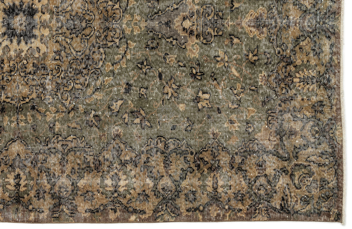 Distressed olive green and brown rug with a faded traditional floral medallion pattern and a fringed edge.