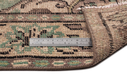Load image 1 in gallery view. Brown and sage green vintage-style rug with a geometric pattern, shown with a metal ruler for scale.