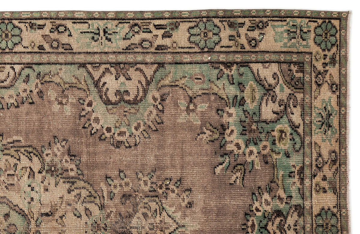 Distressed brown and sage green rug with a traditional floral border and ornate botanical pattern.