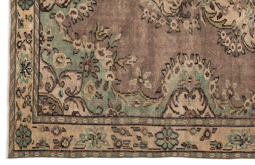 Load image 1 in gallery view. Distressed brown and sage green rug with a traditional floral medallion pattern and a detailed geometric border.