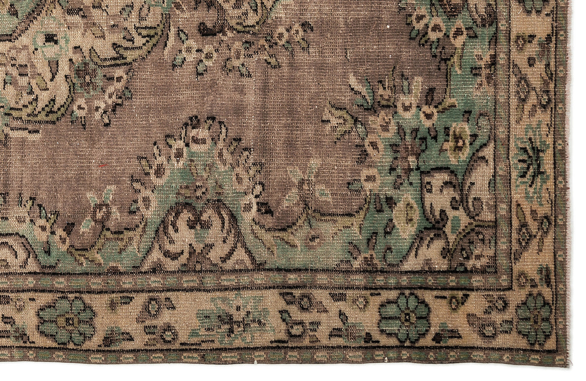 Distressed brown and sage green rug with a traditional floral medallion pattern and a decorative border.