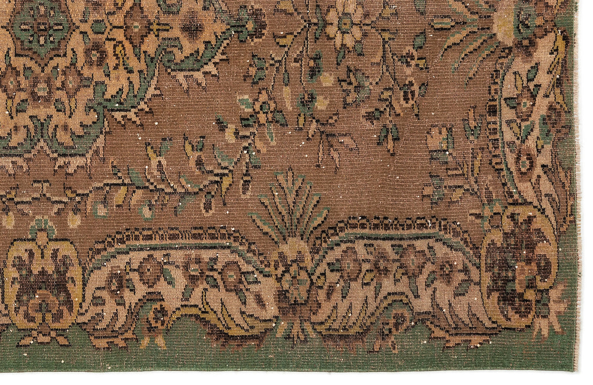 Brown and green traditional rug with a distressed floral pattern and ornate border.