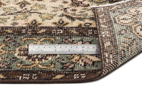 Load image 1 in gallery view. Beige, brown, and sage green traditional floral rug with a folded corner and a metal ruler for scale.
