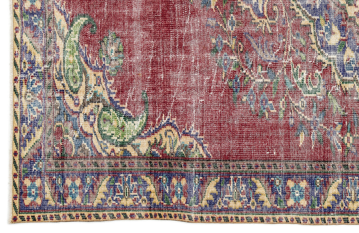 Distressed red rug with a blue and cream paisley-inspired floral pattern and a decorative border.