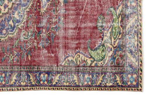 Load image 1 in gallery view. Distressed red, blue, and green vintage-style rug with a traditional floral medallion pattern and a fringed border.