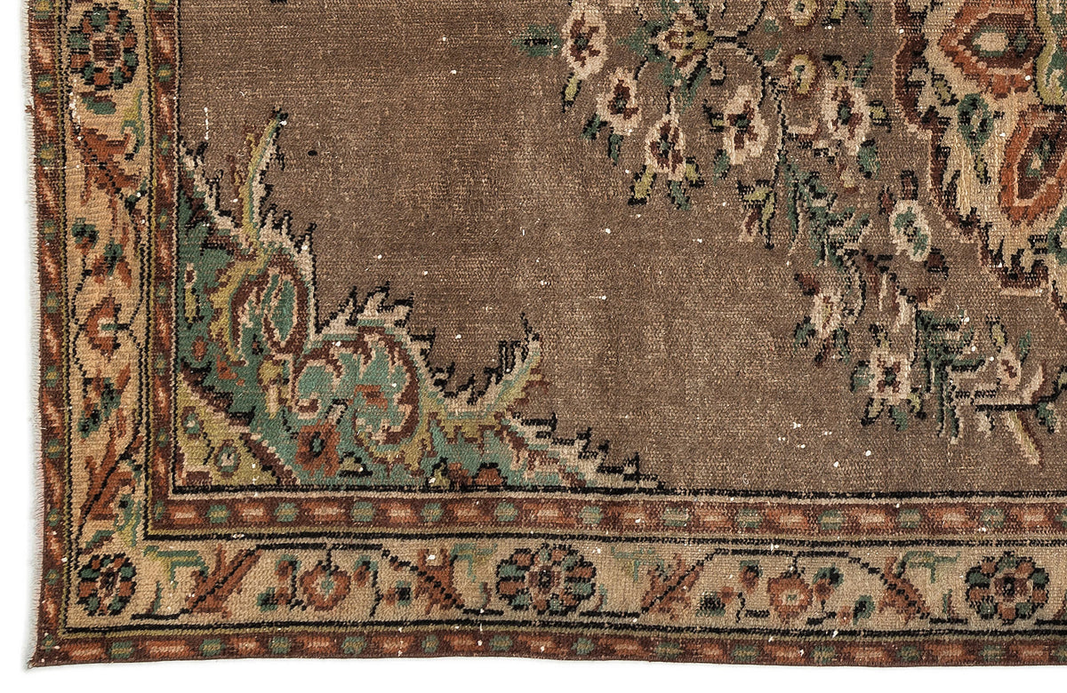 Brown vintage rug with a distressed floral medallion pattern, featuring green, cream, and rust-colored accents.