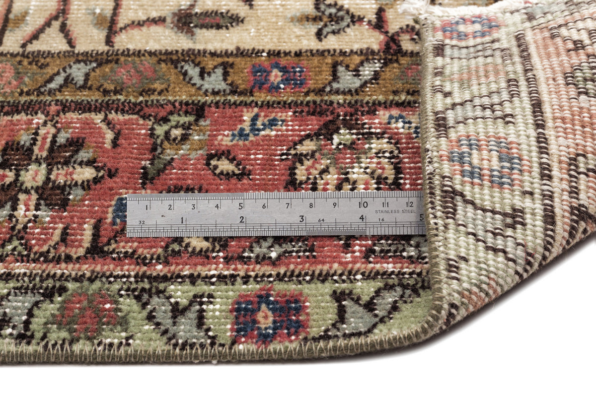 Close-up of a multi-colored traditional floral rug with a metal ruler showing pile texture and woven backing.