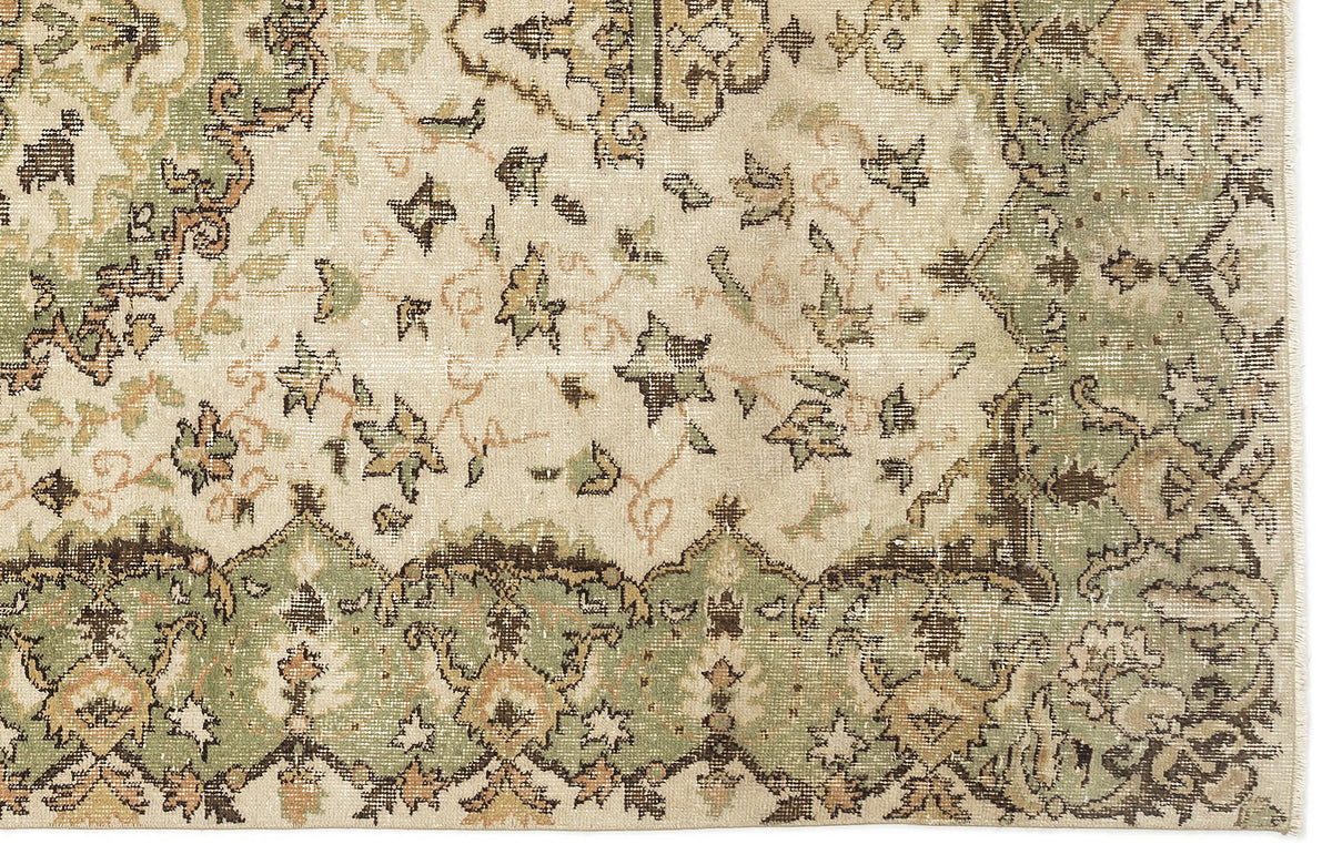 Distressed cream, sage green, and brown rug with a traditional floral medallion pattern and ornate border.