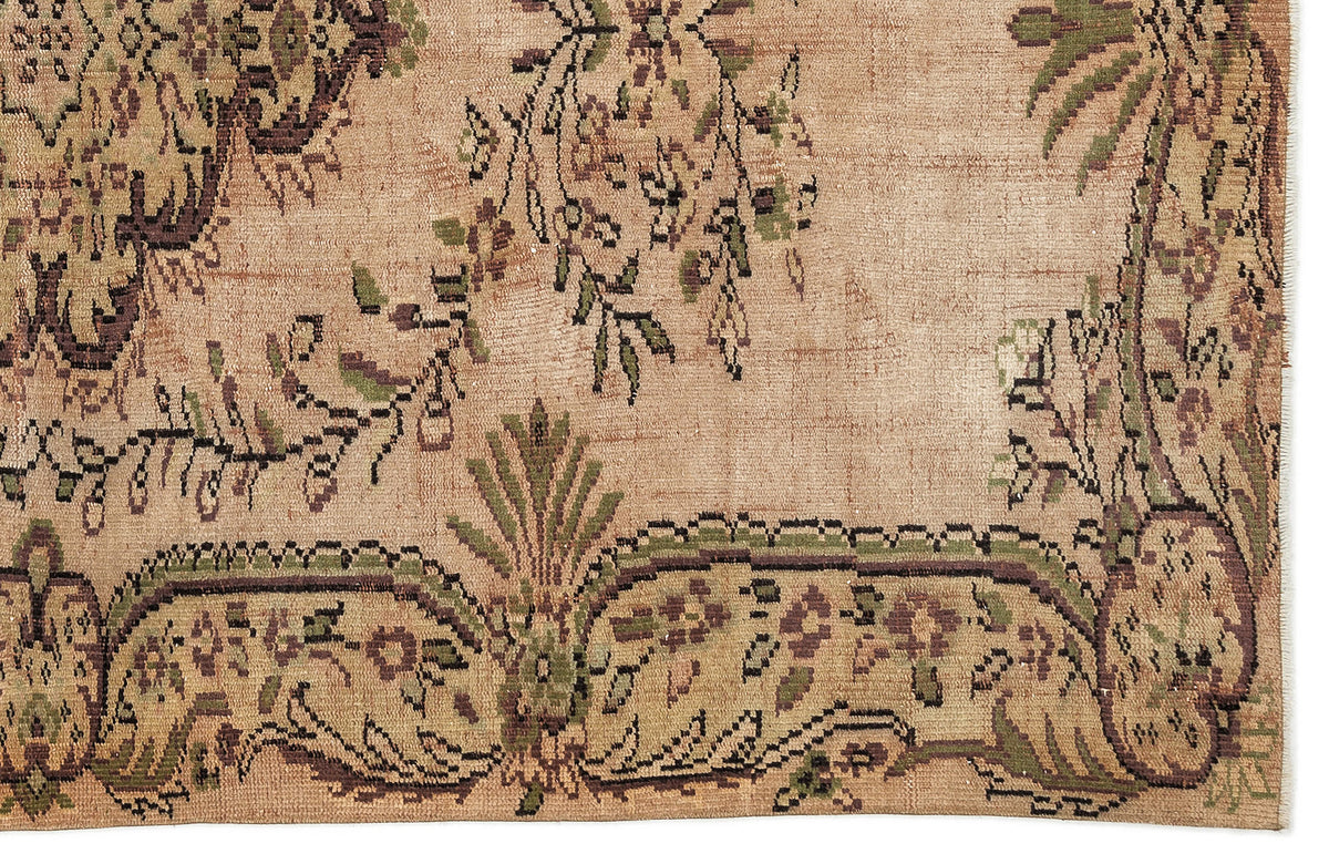 Tan vintage-style rug with a distressed floral and vine pattern in muted green and dark brown.
