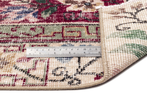 Load image 1 in gallery view. Close-up of a cream, red, and green traditional patterned rug with a metal ruler showing pile height on a white background.