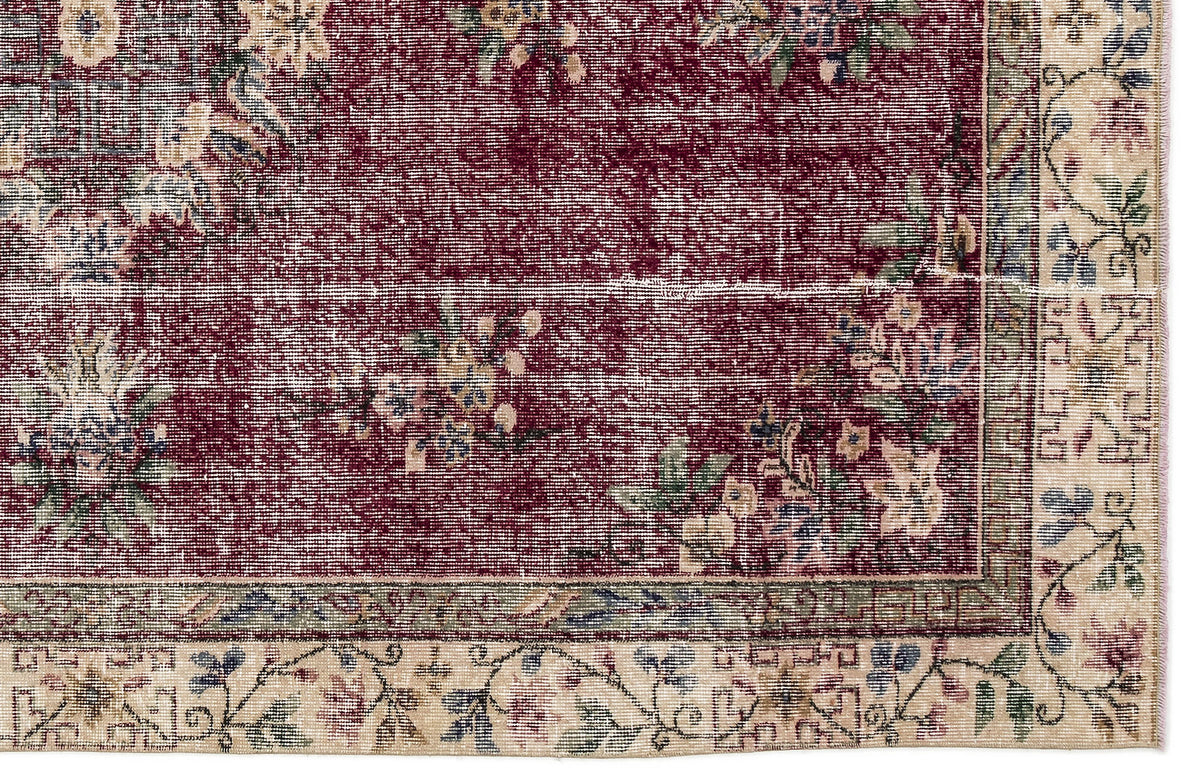 Deep red traditional rug with a distressed floral pattern and a beige border featuring blue and green botanical motifs.