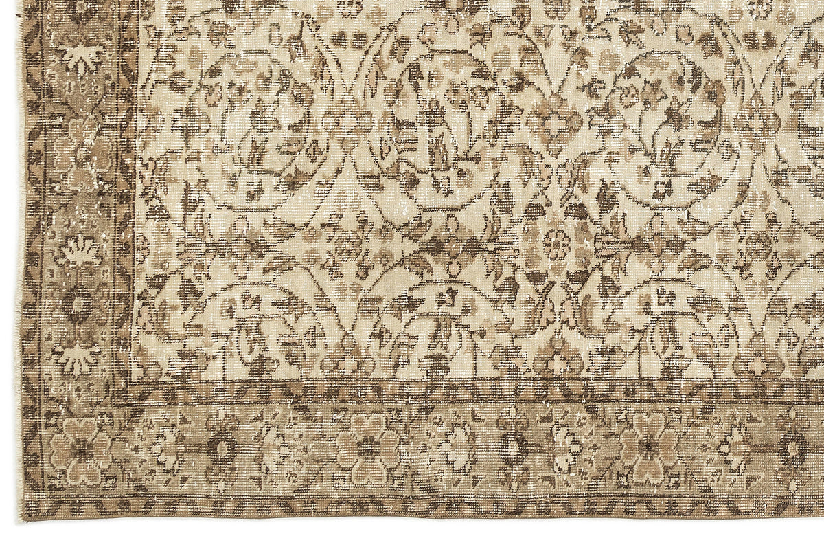 Beige and brown distressed rug with a repeating floral medallion pattern and a decorative border.