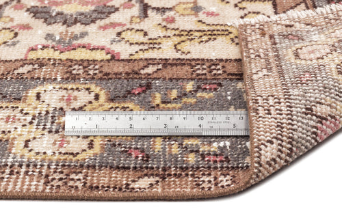 Load image 1 in gallery view. Beige, brown, and muted pink traditional rug with a floral medallion pattern, shown with a metal ruler for scale.