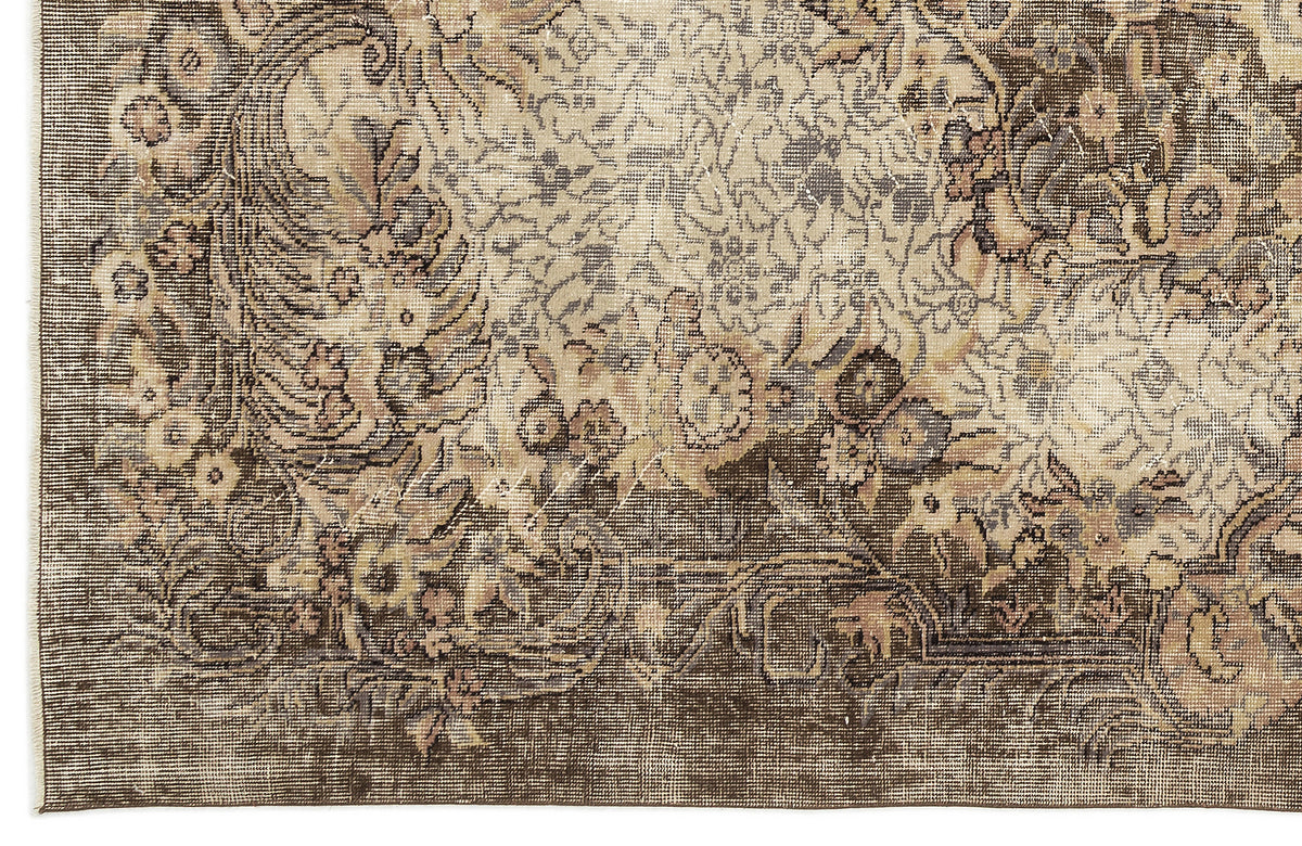 Distressed brown and beige rug with a traditional floral medallion pattern and intricate border detail.
