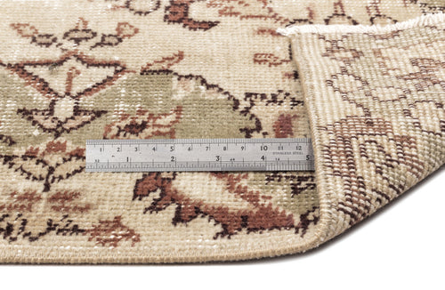 Load image 1 in gallery view. A metal ruler shows inches and centimeters on the Clera - Vintage Medallion Rug (5'7 x 8'10); one corner is folded to reveal the underside and detailed edge stitching.