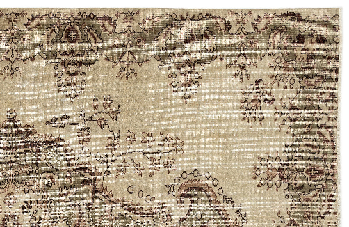 A close-up of the Clera Vintage Medallion Rug (5'7" x 8'10") in beige, showcasing green vintage accents, an intricate floral and scroll border, and a center with faded decorative details.